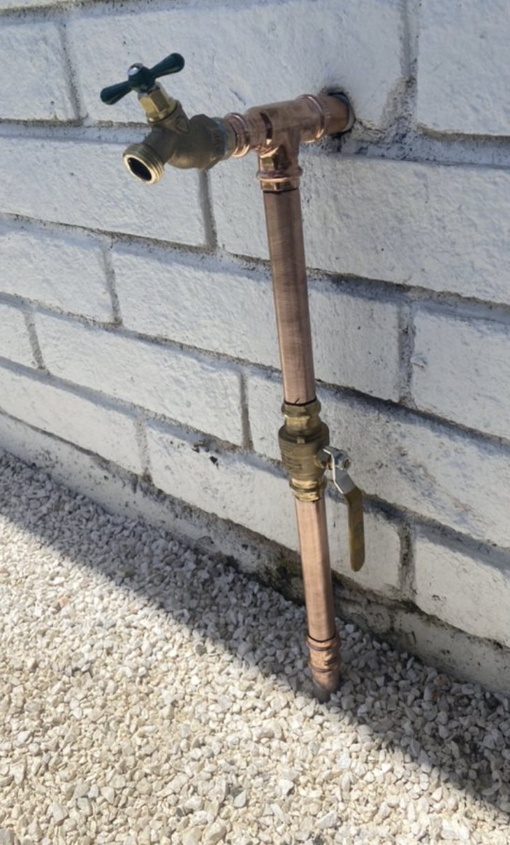 The same spot rebuilt with a clean new copper riser, shut-off valve, and brass hose bibb