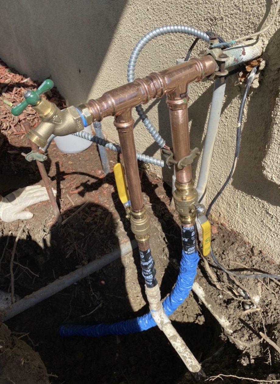 A clean copper backflow and shut-off valve assembly built by Geyser Plumbing